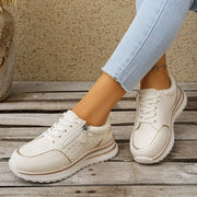 Pair of white sneakers held to show side panels