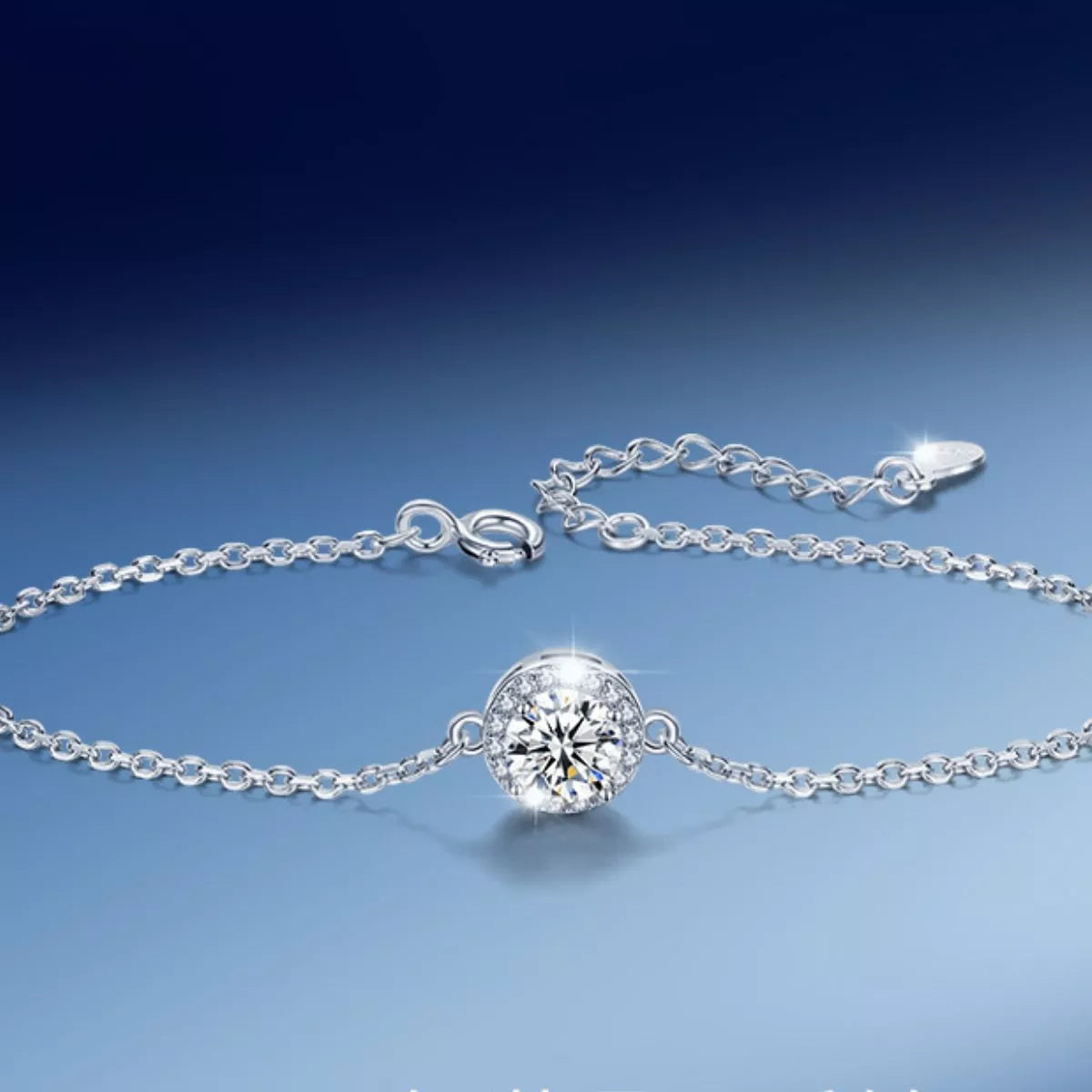 Silver chain bracelet with a round moissanite centerpiece displayed on blue