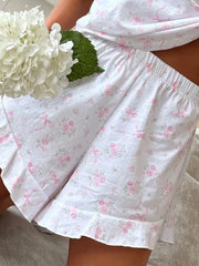 Close-up of white lounge shorts showing pale pink print, elastic waist and ruffled hem