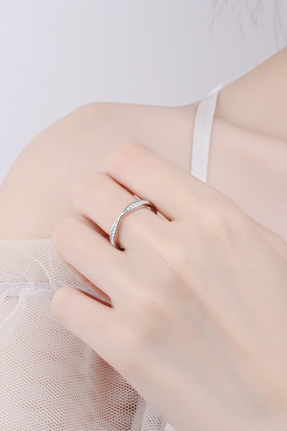 Slim half-eternity ring worn on a hand, shown close up.