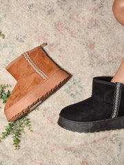 Tan and black round-toe platform boots styled together on a rug