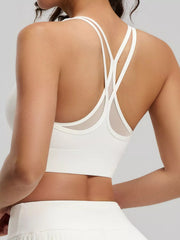 Rear angled view of white active bra with crossed double straps above a white pleated skirt