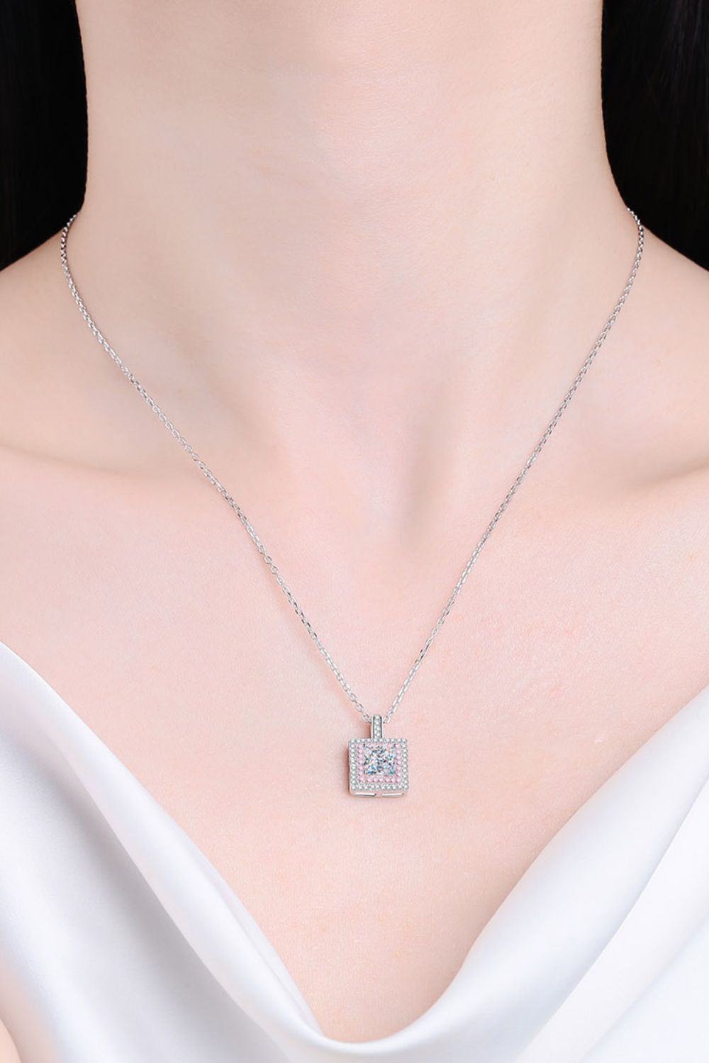 Model wearing a square pendant necklace with a pale pink stone border