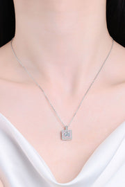 Model wearing a square pendant necklace with a pale pink stone border