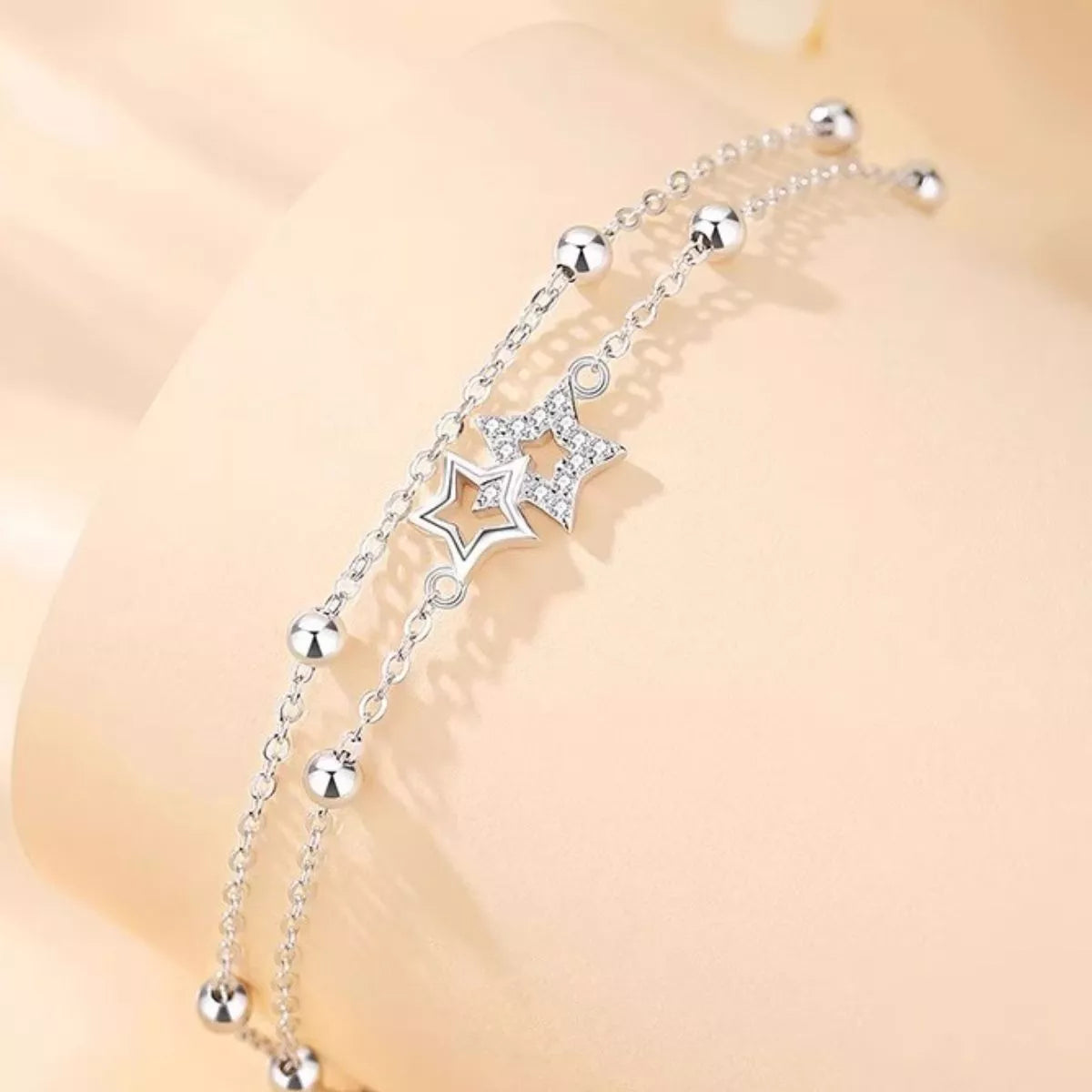 Close-up of two dangling star charms and beads on the silver bracelet