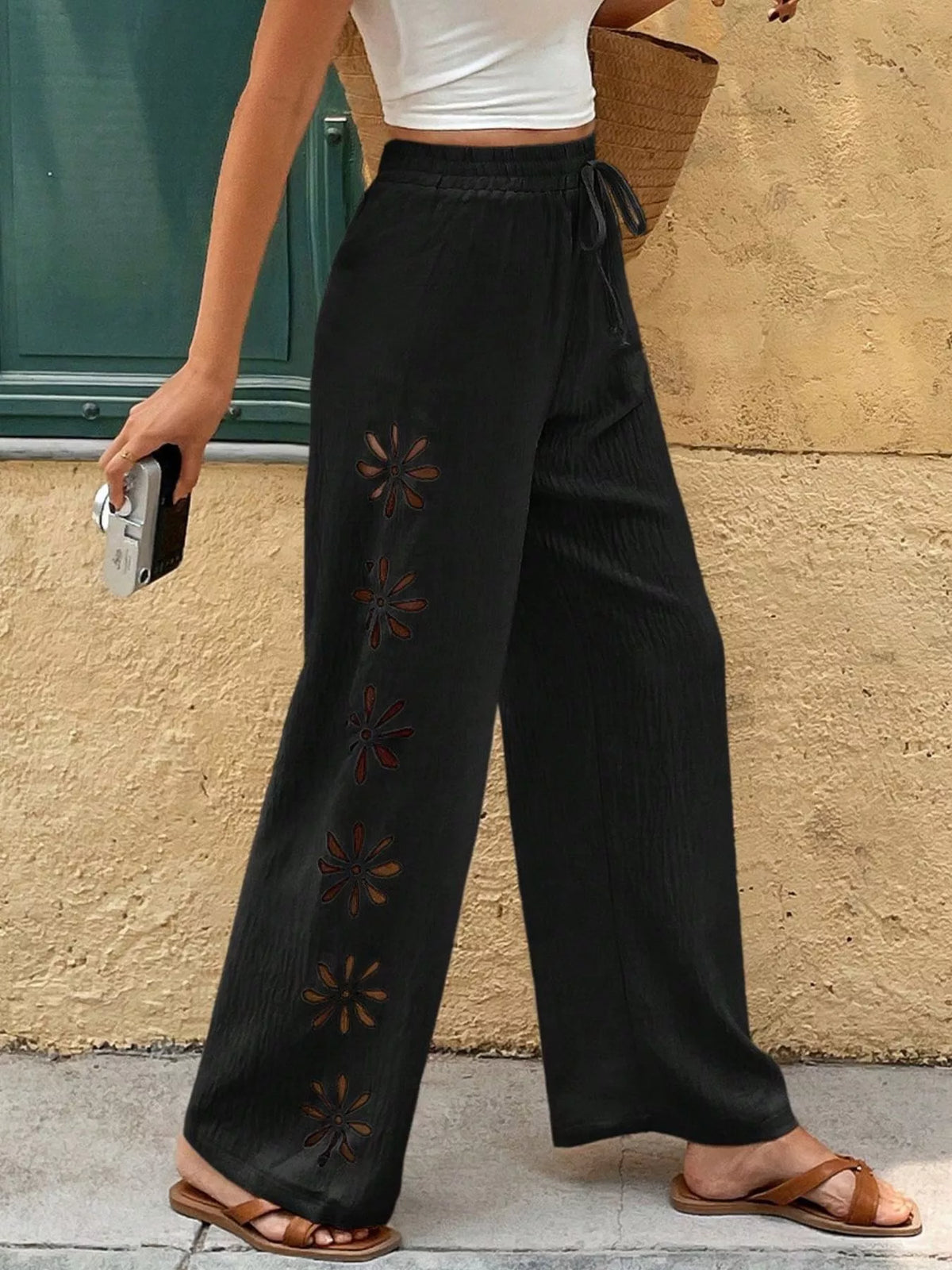 Model wearing black wide-leg pants with floral cutout details