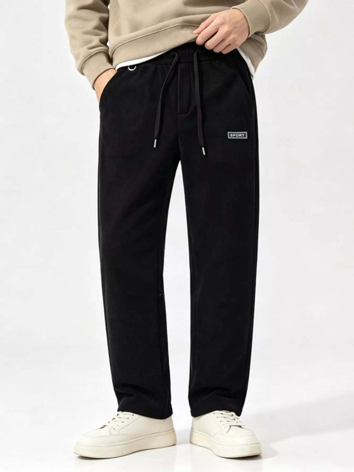 Front view of black wide-leg drawstring pants with a small rectangular thigh label