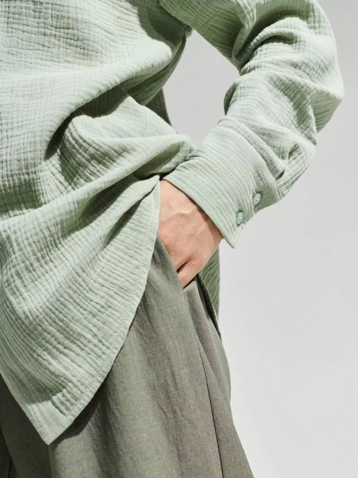 Close view of pale green shirt sleeve and gauze texture.