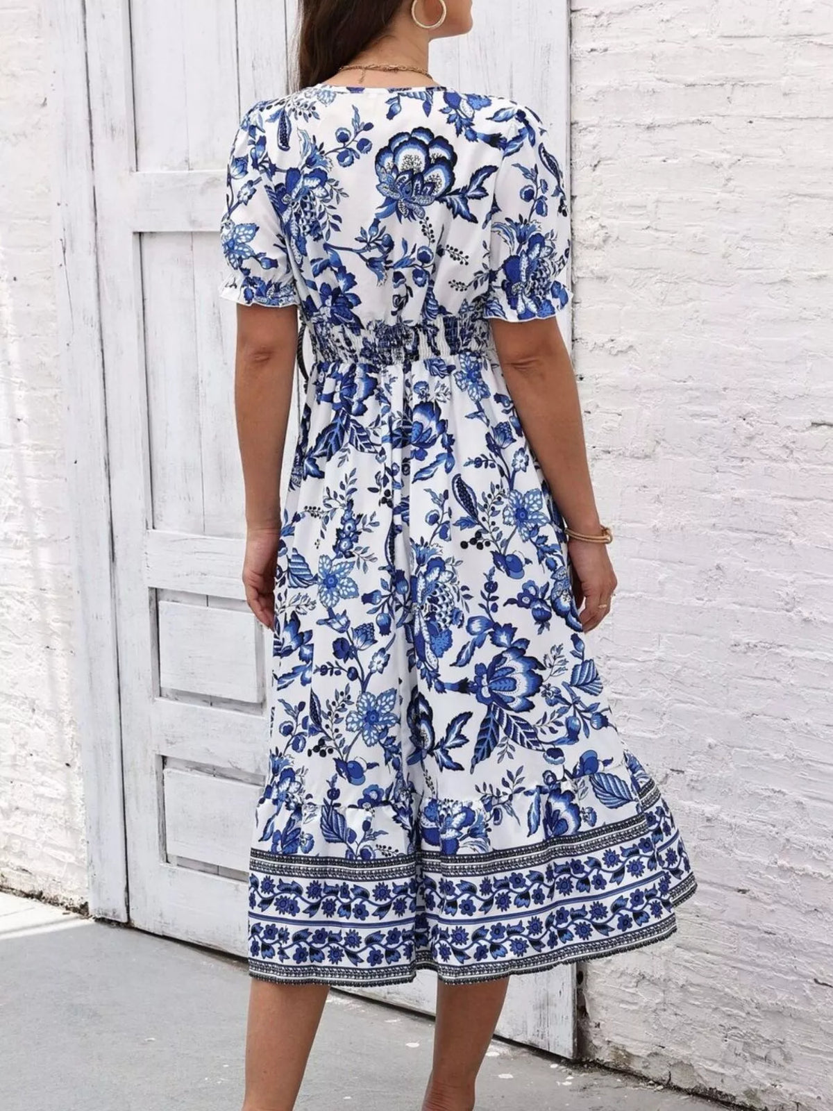 Back view of the blue and white floral puff-sleeve midi dress with a gathered waist.