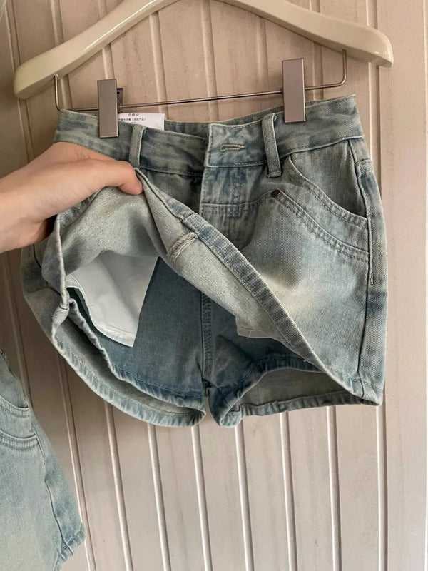 Light-wash high-waisted denim shorts shown from back on hanger