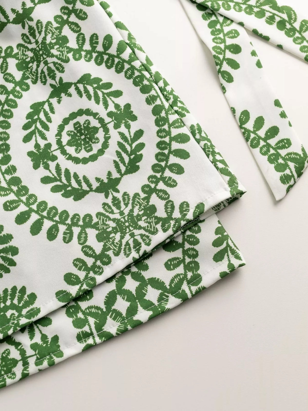 Women's printed tie-waist button-front romper, close-up of green printed fabric