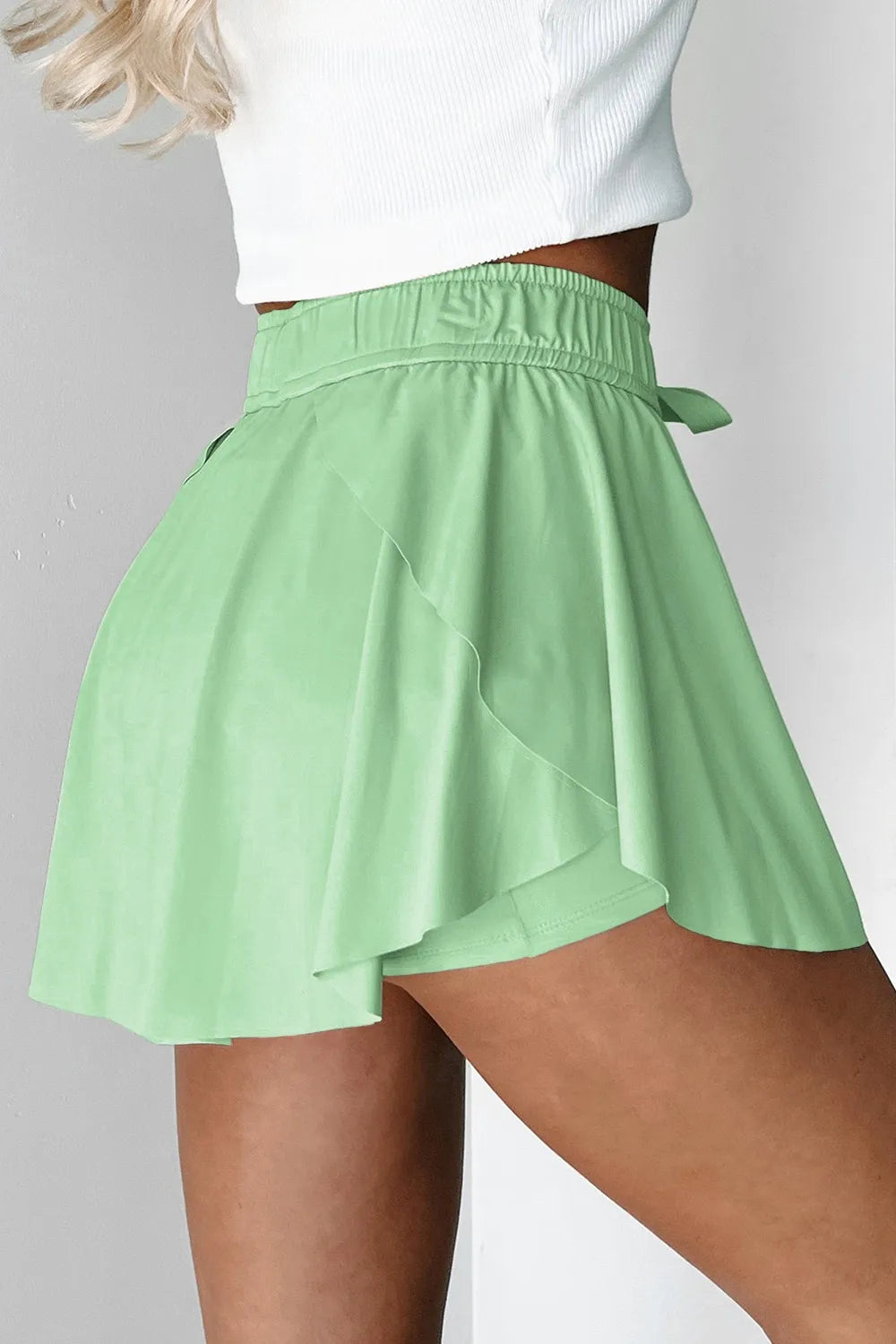 Side view of mint green skort showing the flared overlay over fitted shorts