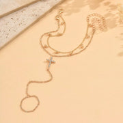 Gold-tone cross bracelet laid out to show its chain and charm