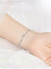 Close wrist view of the delicate silver-tone wavy-link bracelet with zircon flowers