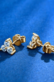 Three-stone moissanite studs viewed from the side on blue surface