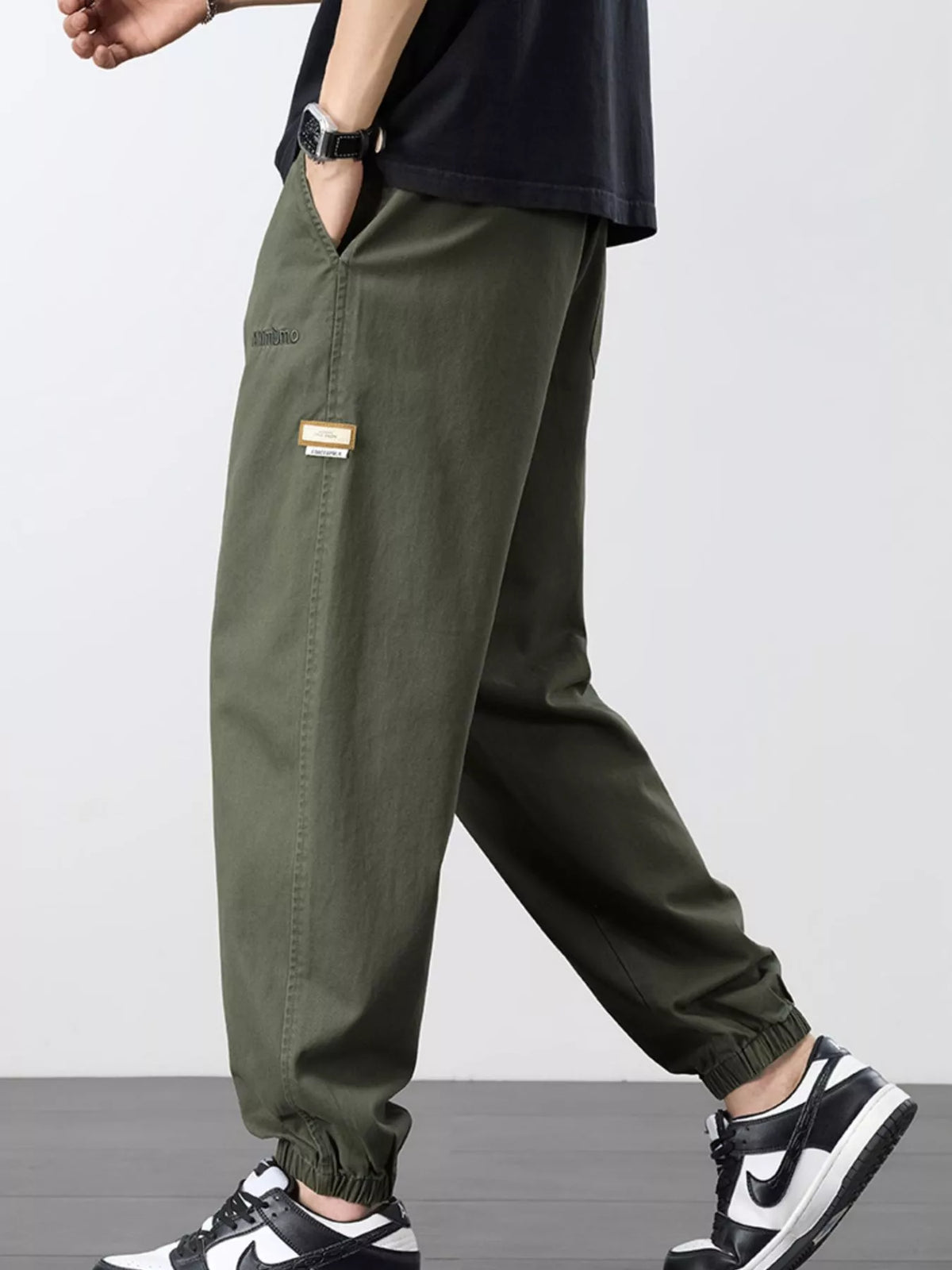 Side view of olive joggers showing the leg seam, side pocket and gathered ankle cuff.
