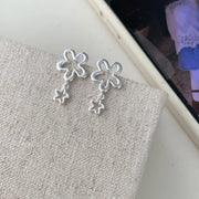 Flower drop earrings displayed on a pale textured surface