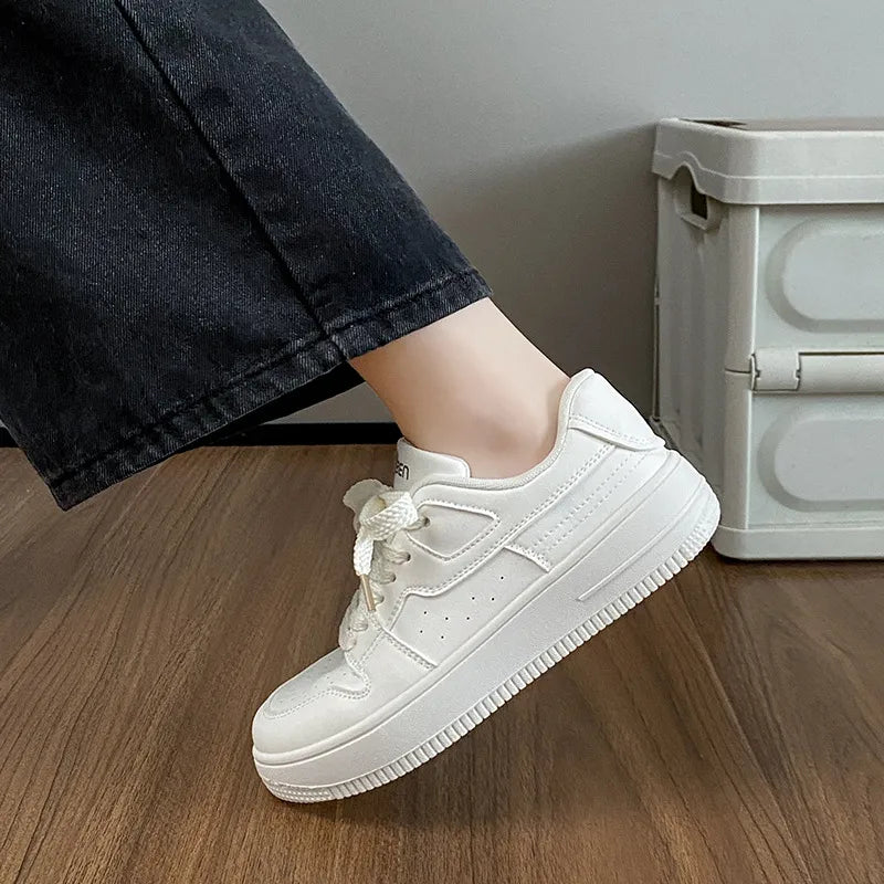 Side view of a white low-top lace-up sneaker with a thick white sole