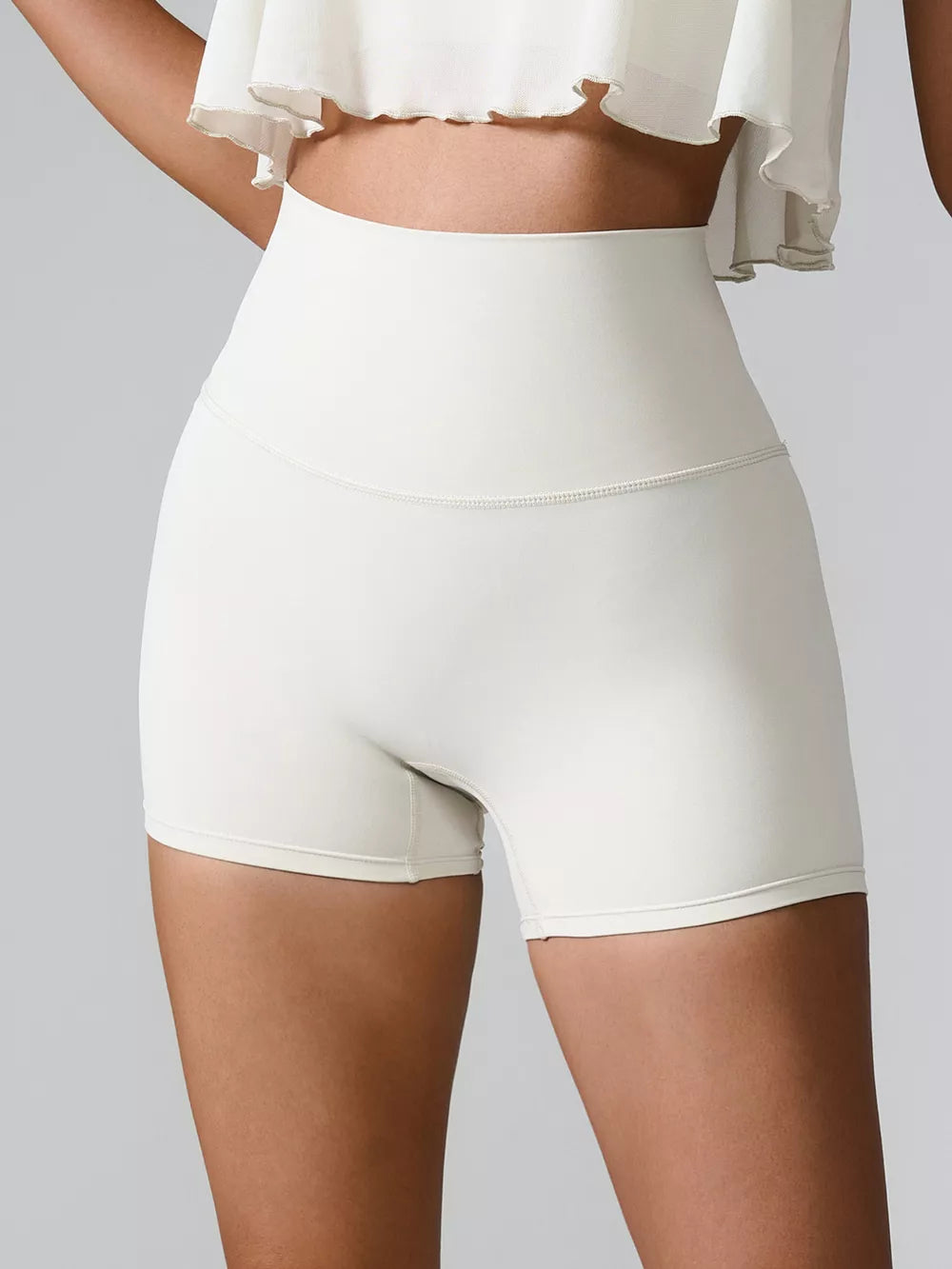 Front view of cream high-waist fitted shorts with a wide waistband.