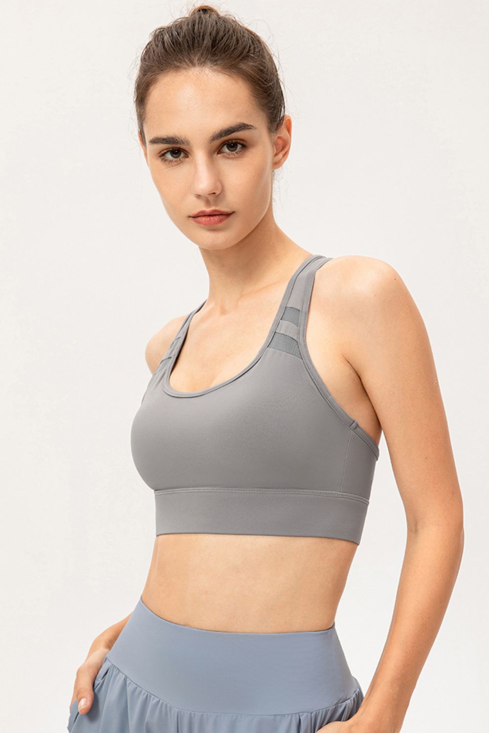 Model wearing gray scoop-neck sports bra, angled front view