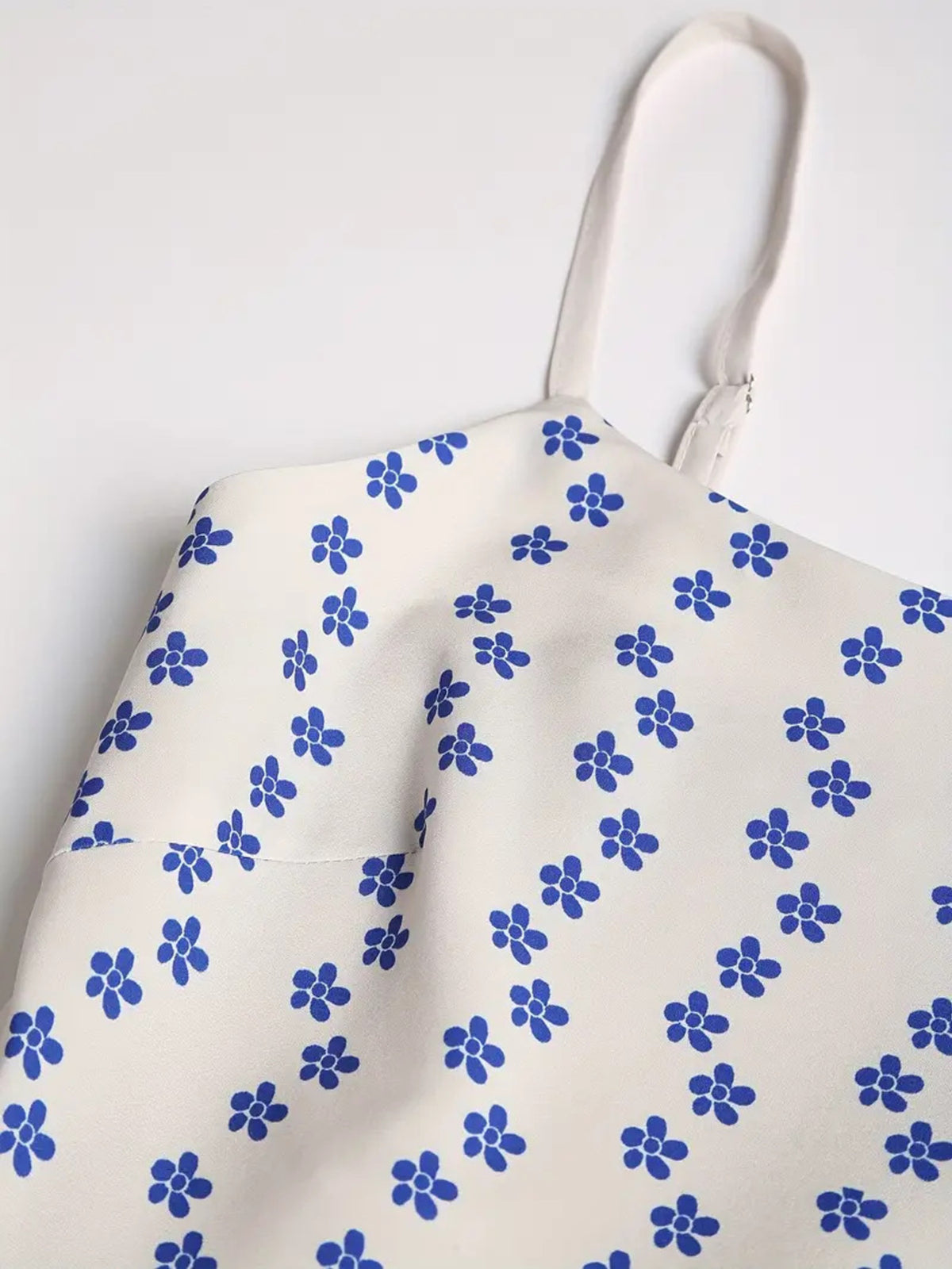 White spaghetti strap and upper bodice with small blue flowers shown close up.