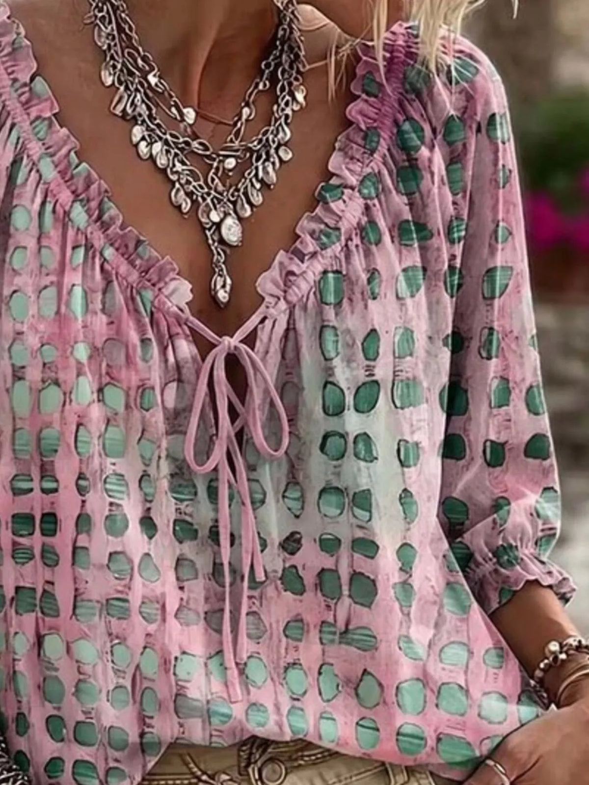 Pink printed blouse shown at an angle with its gathered sleeve and loose hem.