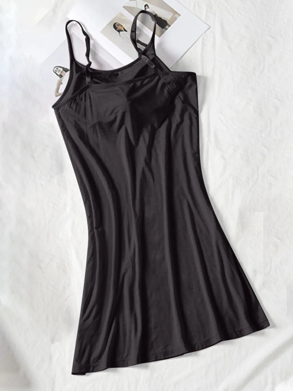 Black spaghetti-strap cami dress laid flat with a softly flared skirt