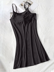 Black spaghetti-strap cami dress laid flat with a softly flared skirt