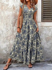 Front view of blue floral maxi dress showing cap sleeves, a smocked waist and a full tiered skirt.