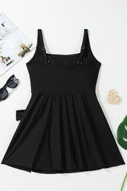 Flat lay of the black swim dress showing wide straps, gathered skirt and side ties.