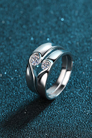 Angled view of a sculptural rhodium-plated ring with two moissanite stones on teal.