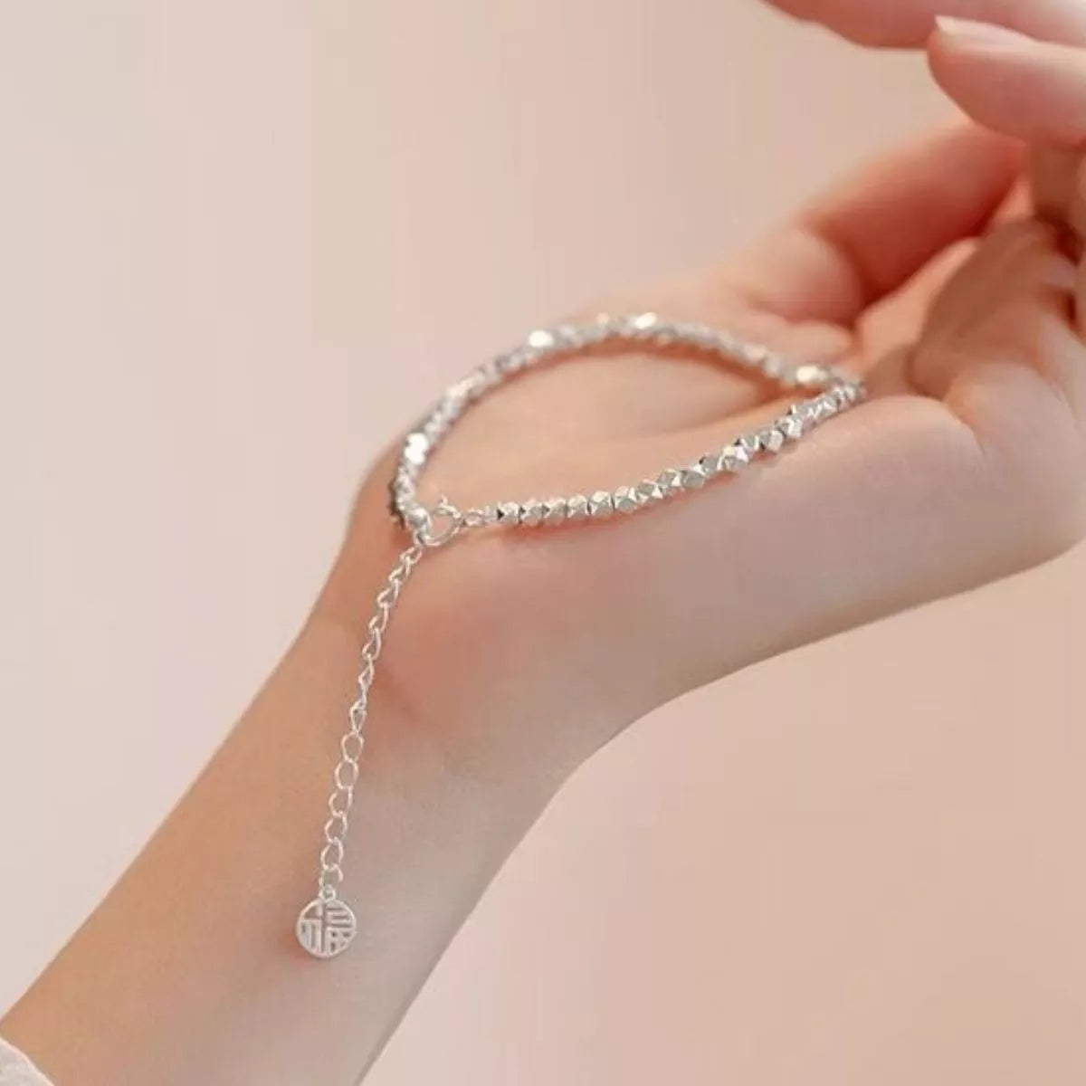Bracelet draped over hand showing adjustable extension and charm