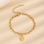 Gold-tone chain bracelet with round LOVE letter charm on a light surface