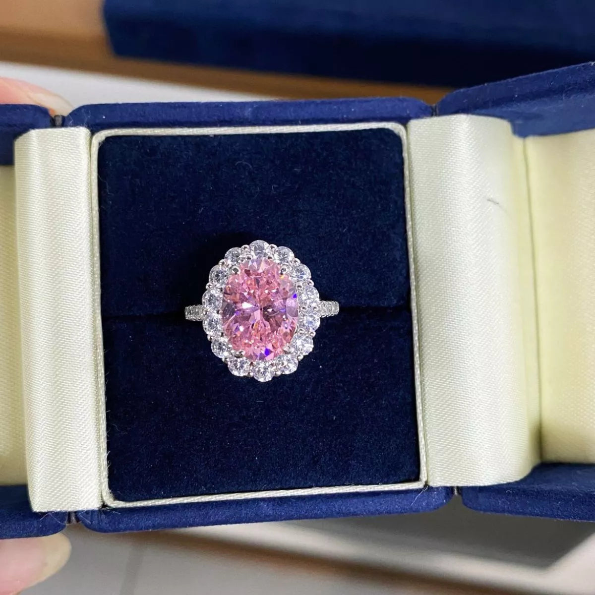 Blush pink oval centre stone ring displayed in its open box.