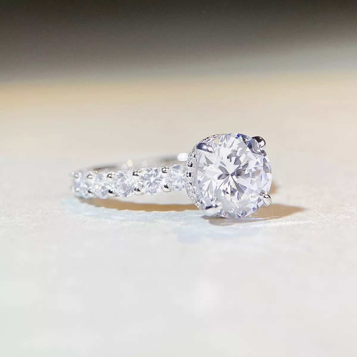 Close-up of the round clear center stone and sparkling band on a light surface.