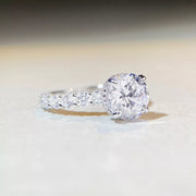 Close-up of the round clear center stone and sparkling band on a light surface.