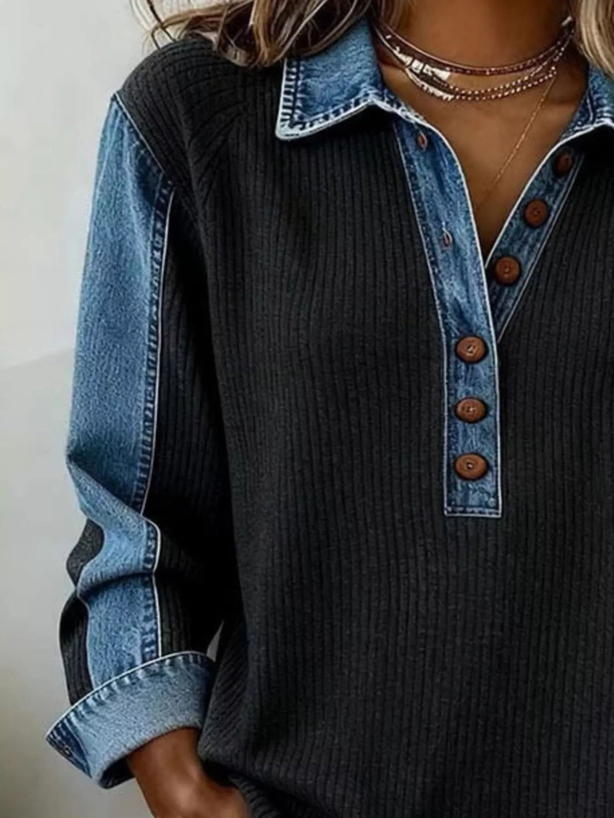 Model wearing black sweatshirt with denim sleeves and trim