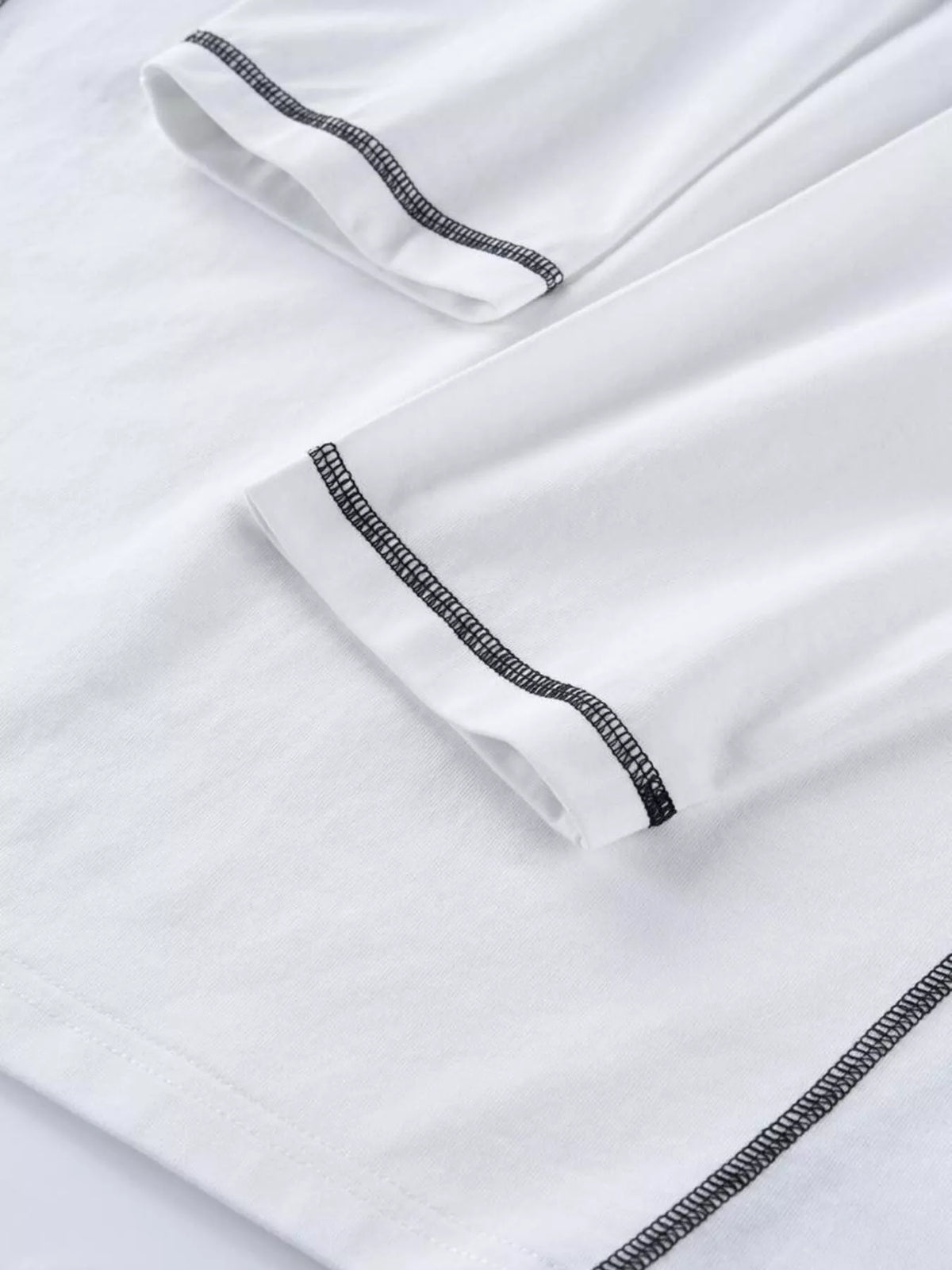 Close-up of black contrast stitching on white long-sleeve T-shirt fabric