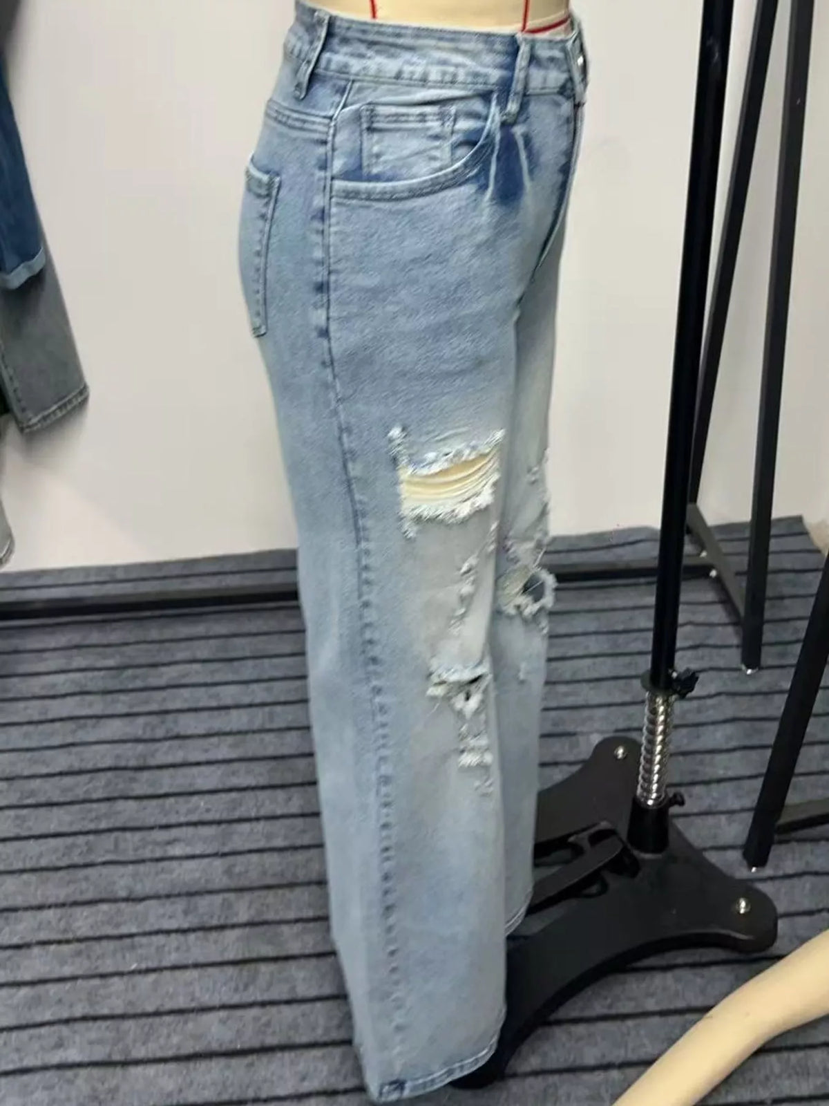 Side view of distressed light-wash wide-leg jeans displayed on a dress form