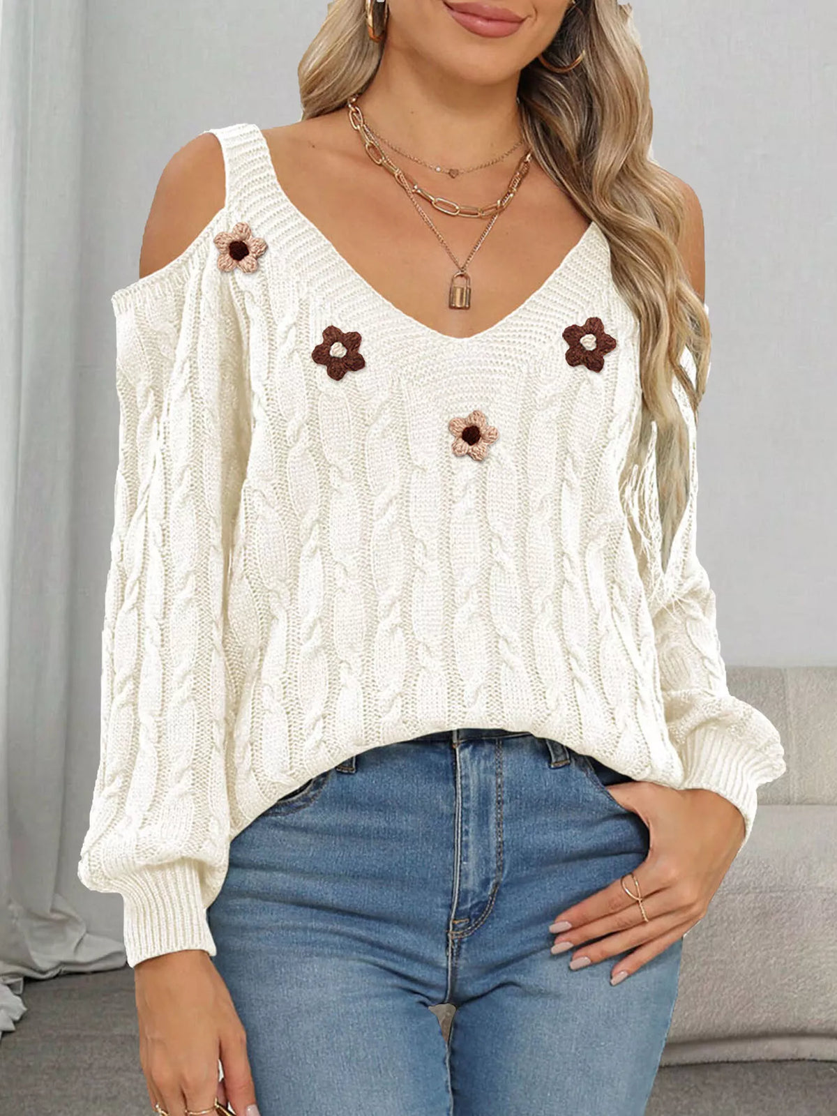 White cable-knit cold-shoulder sweater with pink and brown floral appliqués