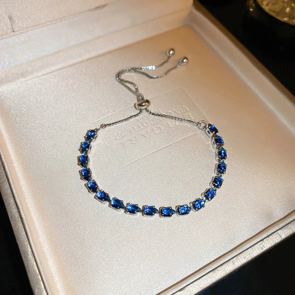 Blue oval stones set in a slim silver-tone bracelet shown on a presentation cushion