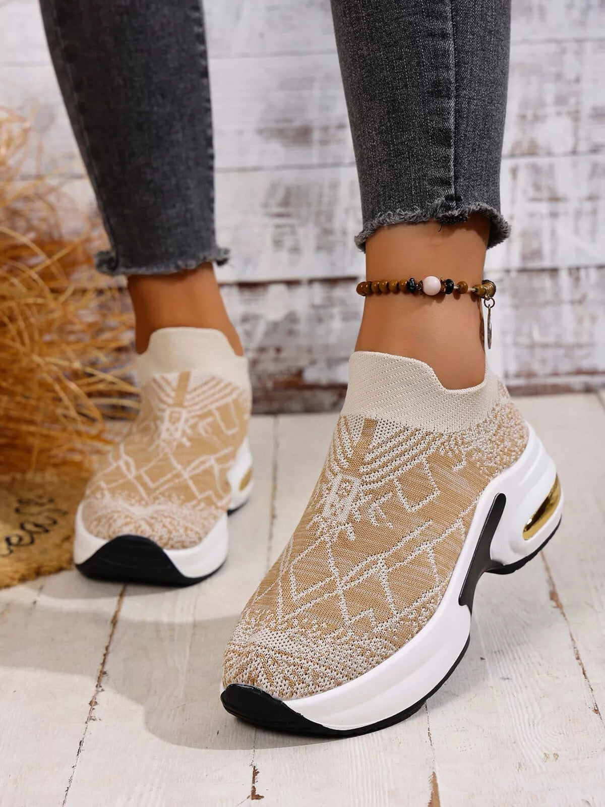 Front angled view of beige mesh trainers with white collars and black toe accents