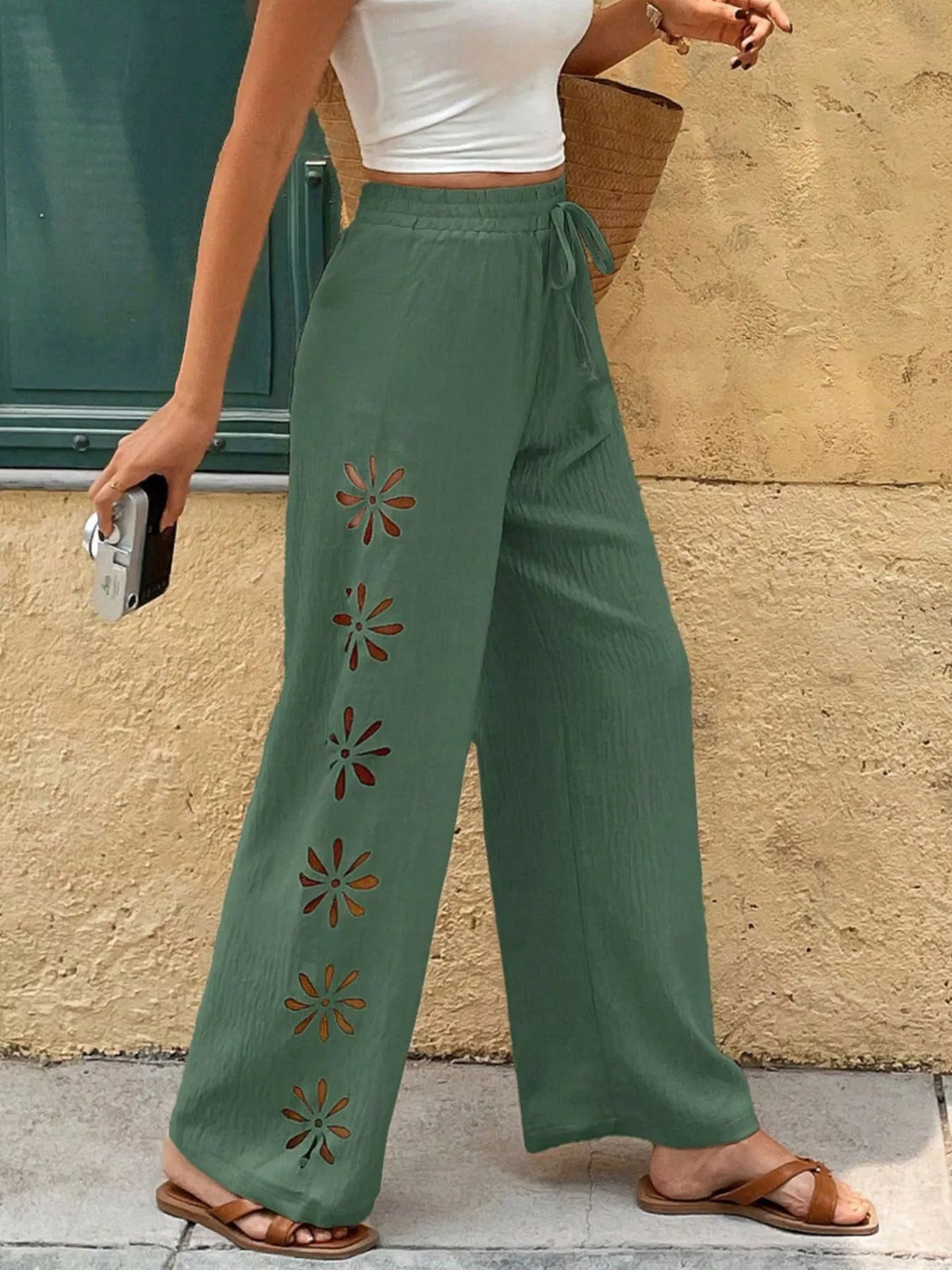 Close view of sage green wide-leg pants and embroidered flowers