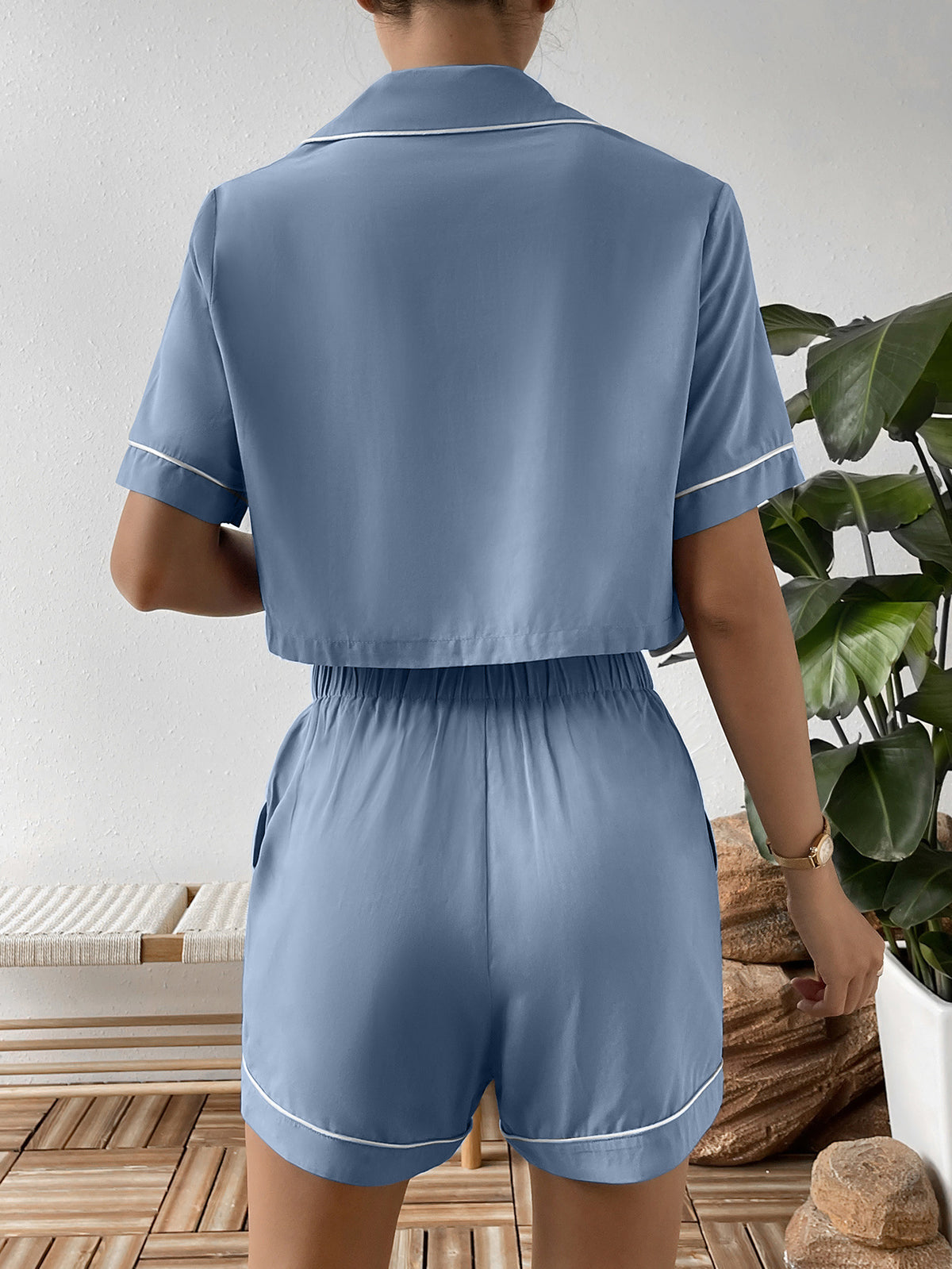 Back view of blue cropped shirt and elastic-waist shorts with white piping