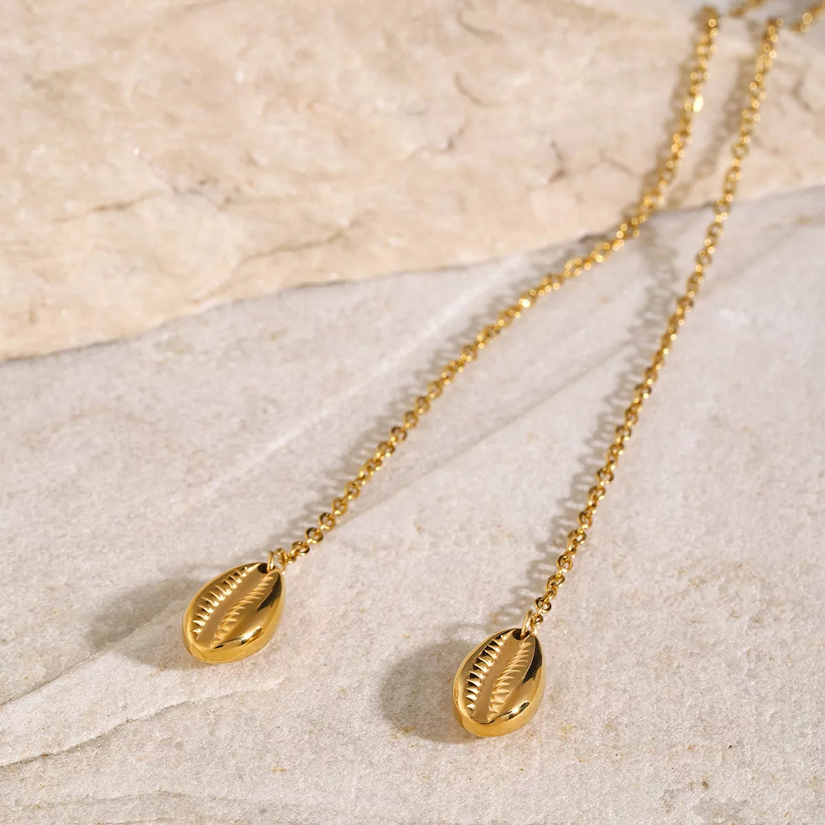 Close view of two gold oval charm drops on the fine chain