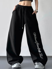 Front view of black wide-leg drawstring pants with white script