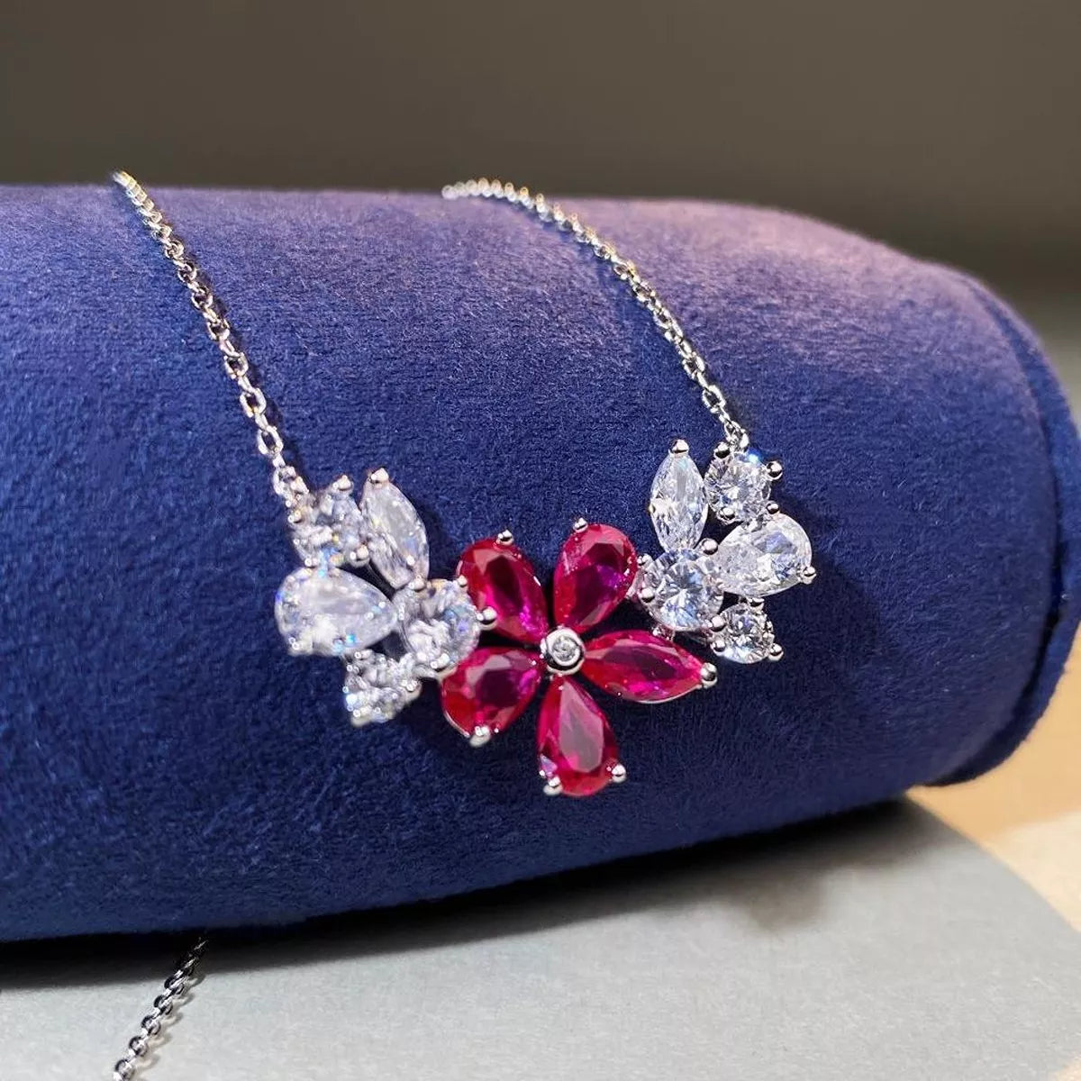 Cerise pink flower pendant necklace displayed on blue cushion