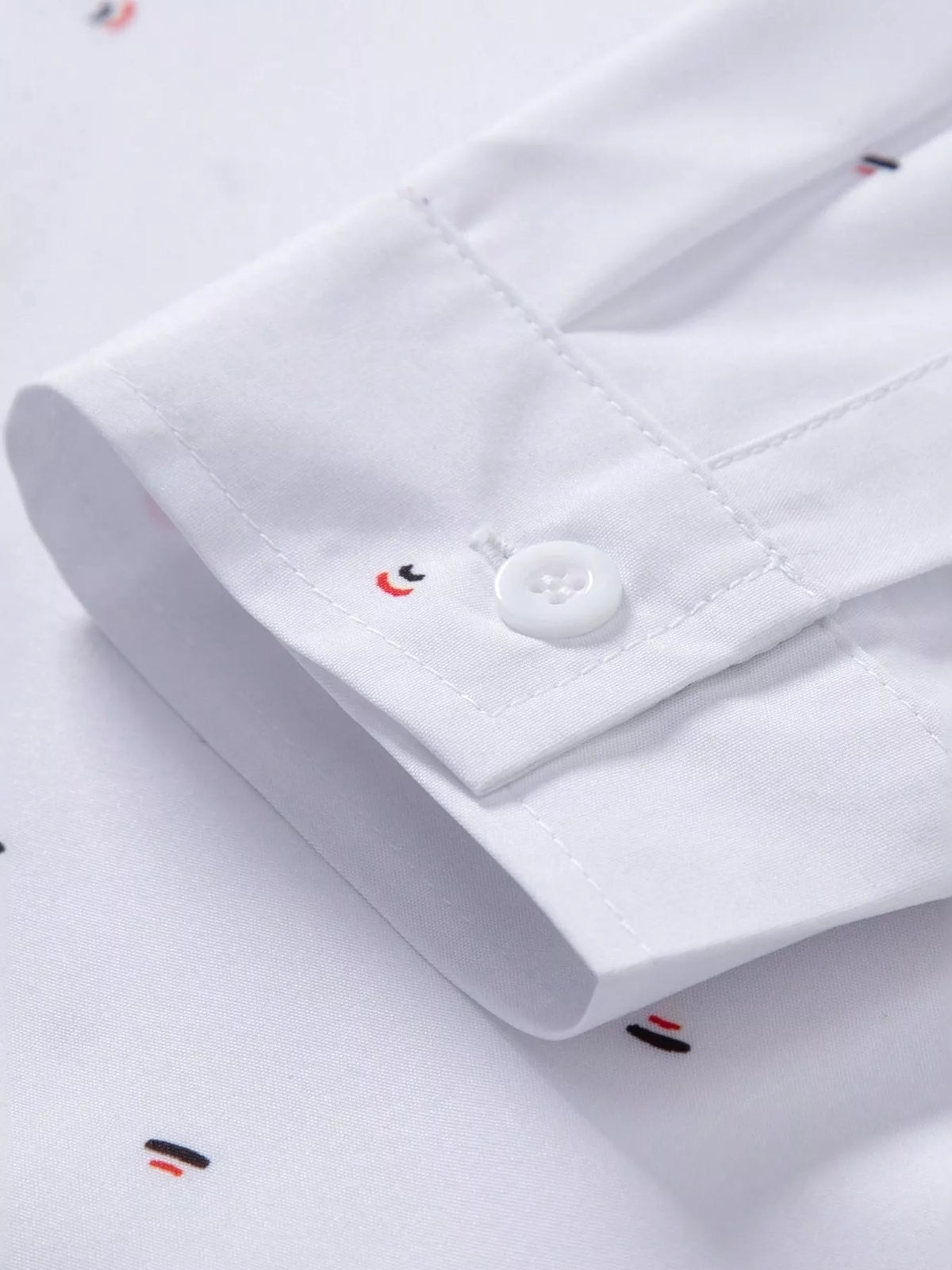 Close-up of white shirt sleeve cuff showing its button and printed motif