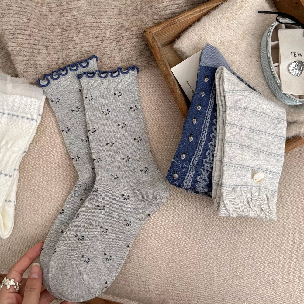 Pair of gray patterned socks with navy scalloped cuffs laid flat