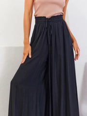 Model seated in navy wide-leg pants